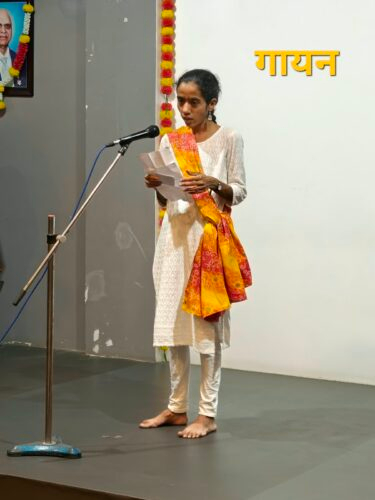 गायन (Singing) – A participant performing a song during the Mental Health Week Talent Show on 6th October 2026. Participant singing into a microphone during the Mental Health Week Talent Show at SAA